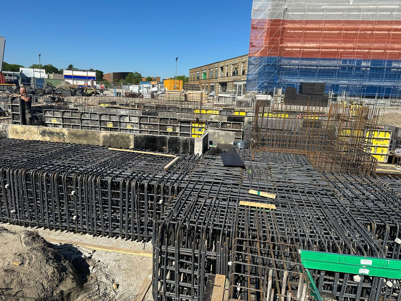 Funderingsbalken met wapening, met de hoogbouw in de steigers op de achtergrond