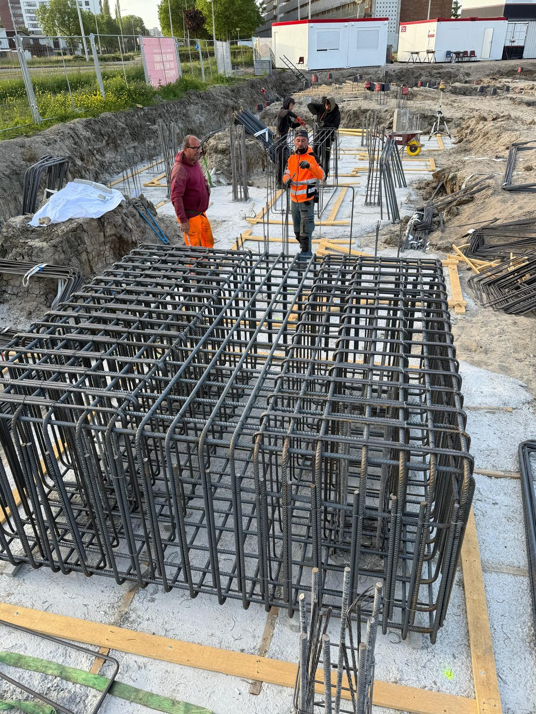 Vlechters aan het werk op een wapeningskorf in de bouwkuip